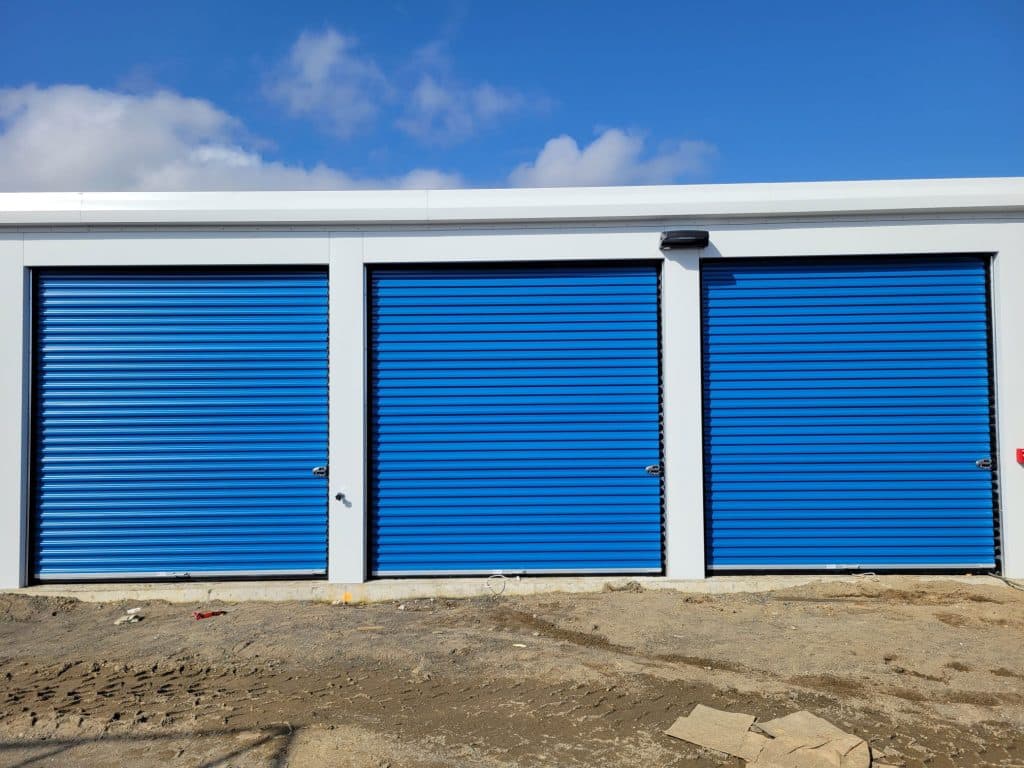 Row of outdoor drive-up storage units with blue roll-up doors at All Access Storage Parksville.