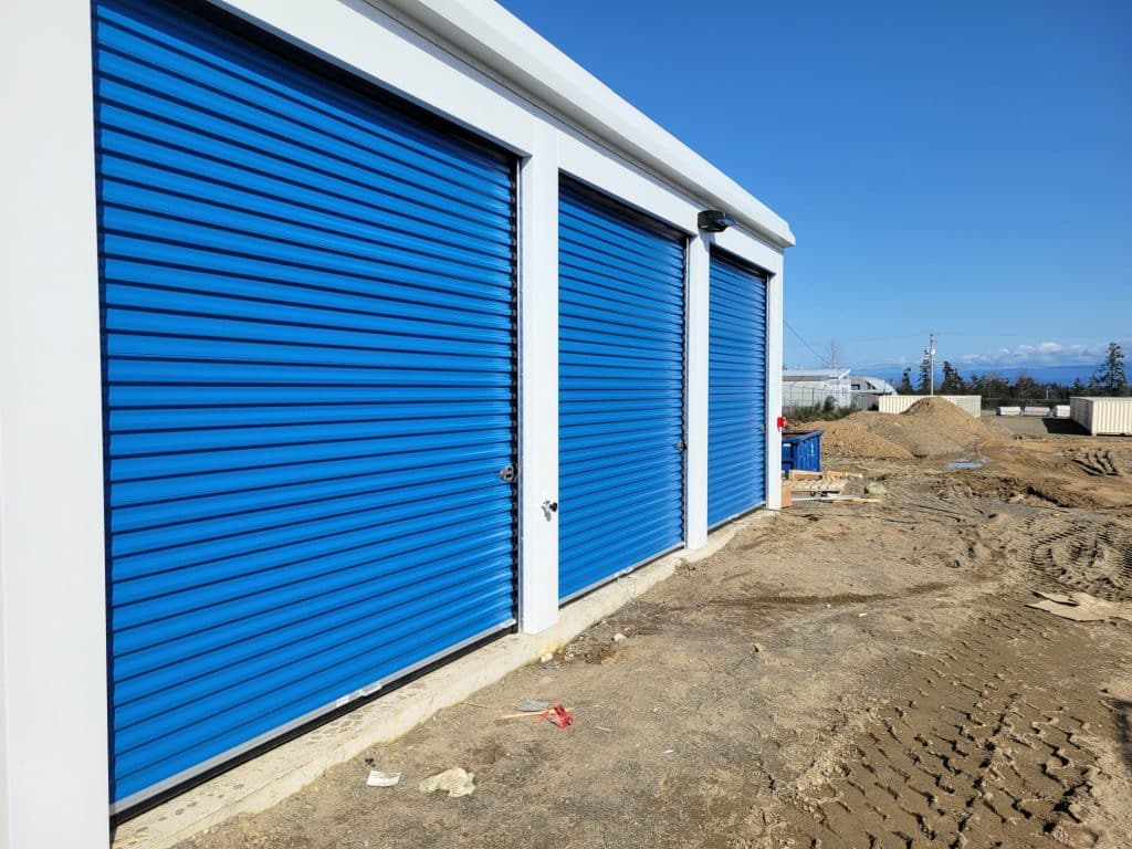 Row of outdoor drive-up storage units with blue roll-up doors at All Access Storage Parksville.