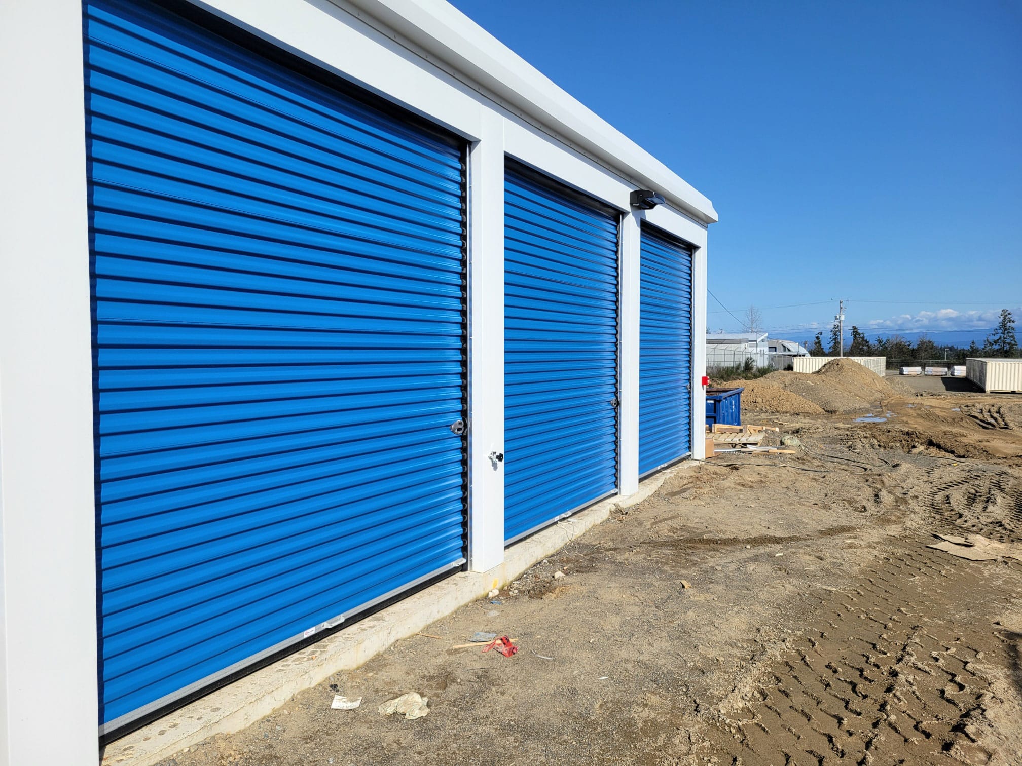 Row of outdoor drive-up storage units with blue roll-up doors at All Access Storage Parksville.